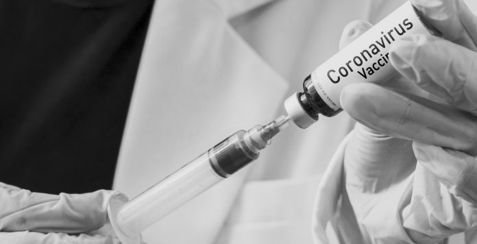 Doctor injecting the syringe to the vaccine bottle